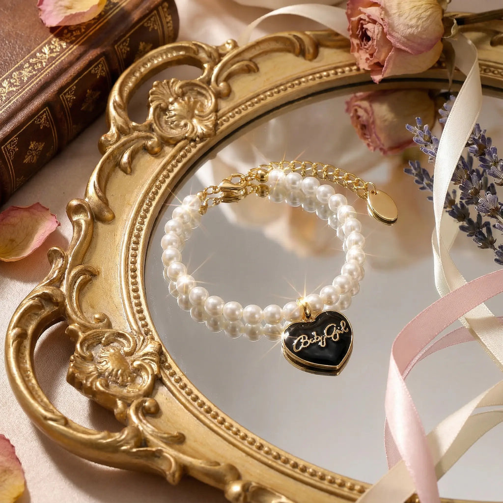 Macro close-up of heart-shaped charm showing glossy enamel filling and 18k gold plated Babygirl lettering