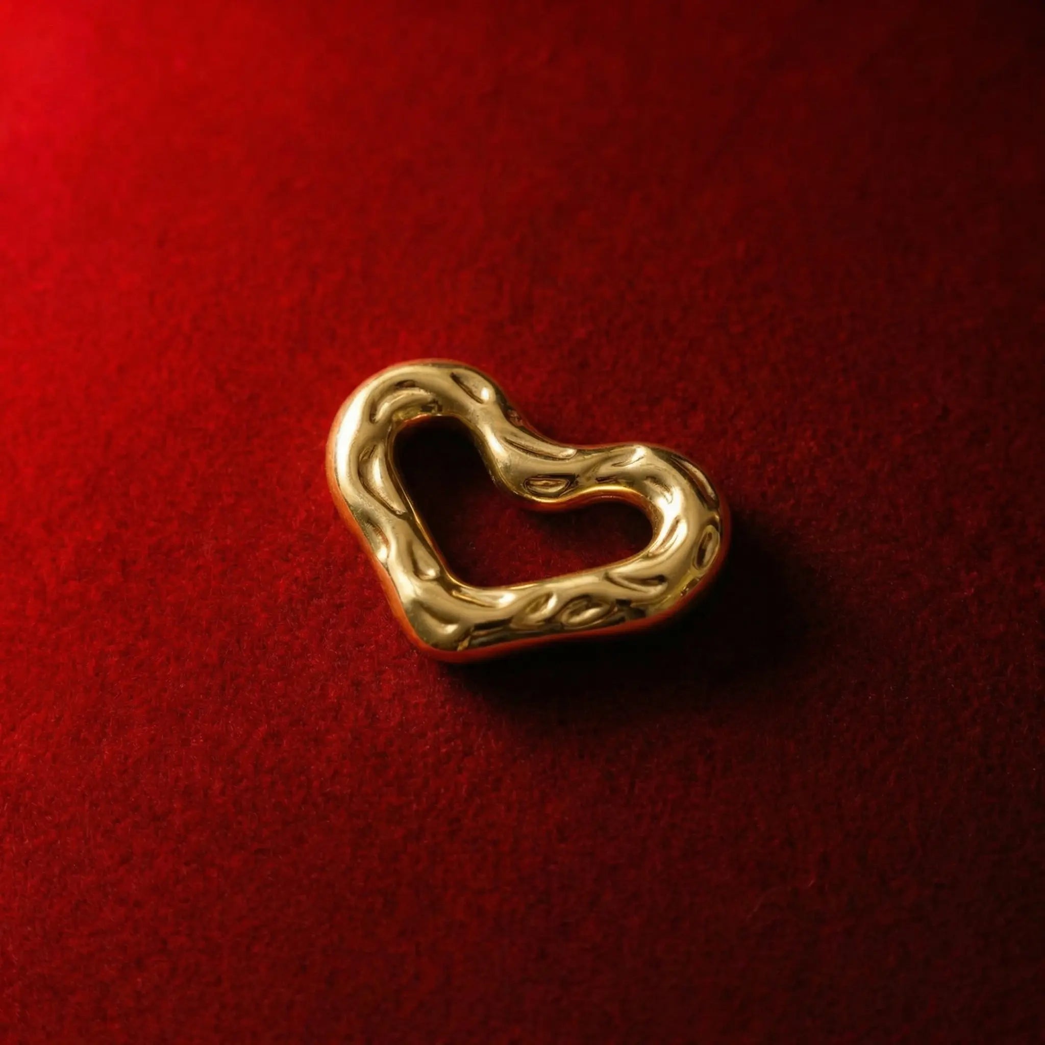 Sculptural gold heart jewelry piece with fluid, curving lines