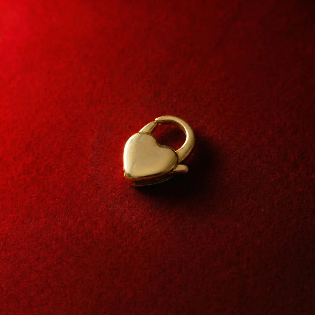 A substantial gold heart-shaped pendant clasp that can be attached to a necklace or bracelet