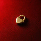 A substantial gold heart-shaped pendant clasp that can be attached to a necklace or bracelet